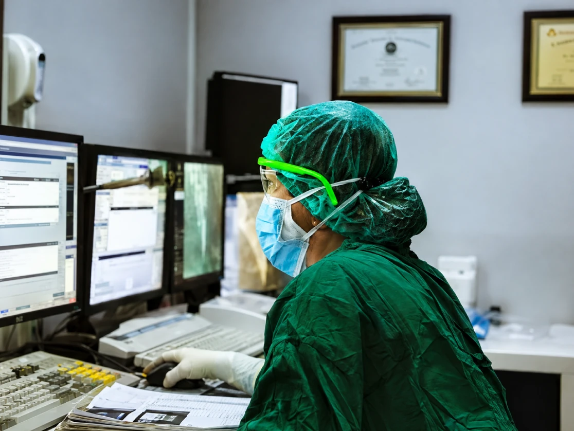 Maria Gatchalian wearing protective equipment working at a hospital computer workstation