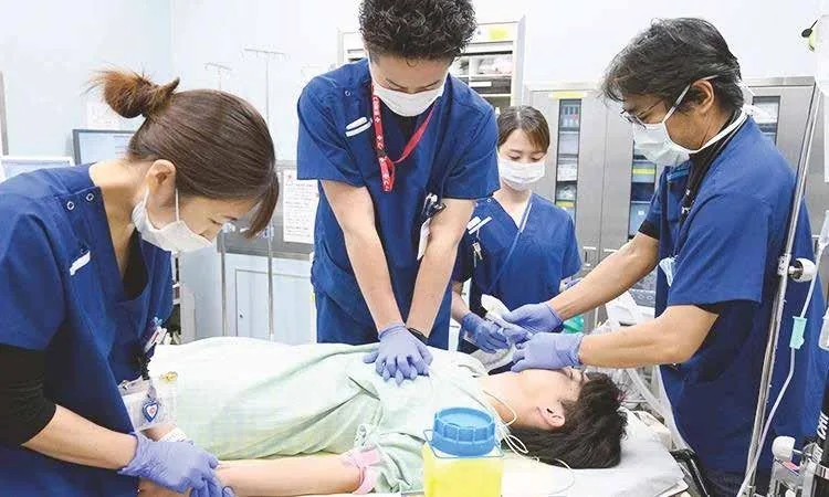 Hospital doctors and nurses performing emergency resuscitation and critical care on a patient in the emergency department